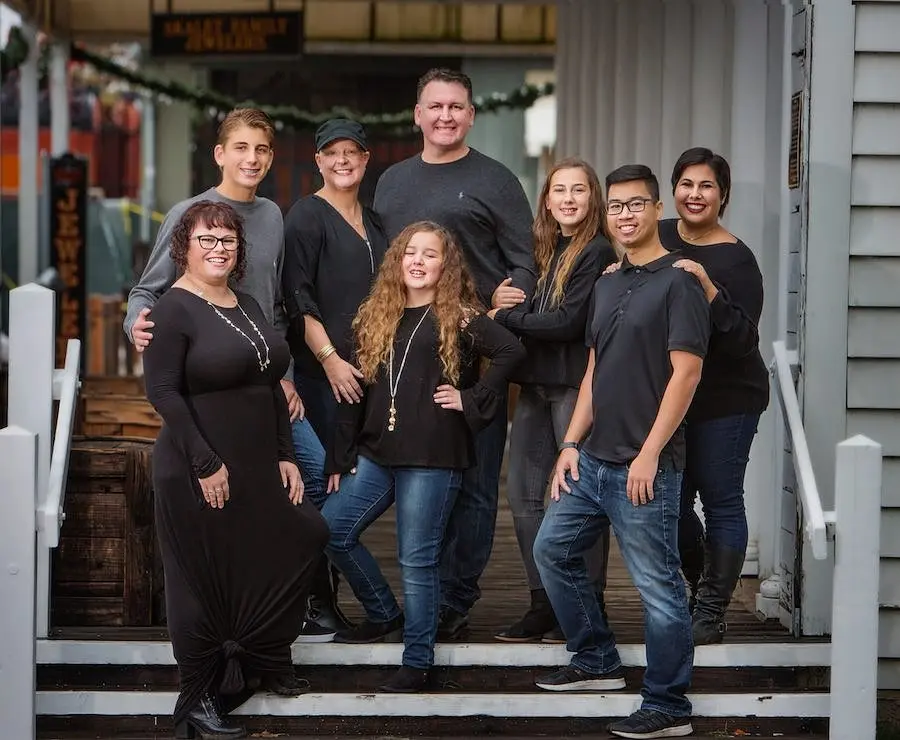 Dr. Espinosa, back row in the middle, with his family on the steps of a porch, everyone dressed in black