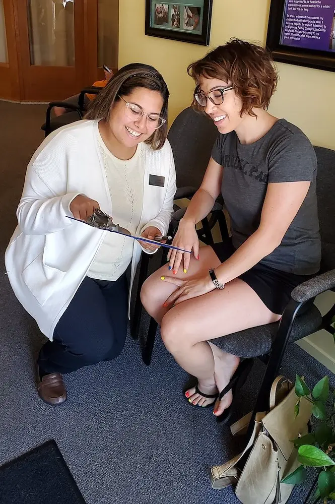 A team member in a white coat going over paperwork with a new patient in the waiting room